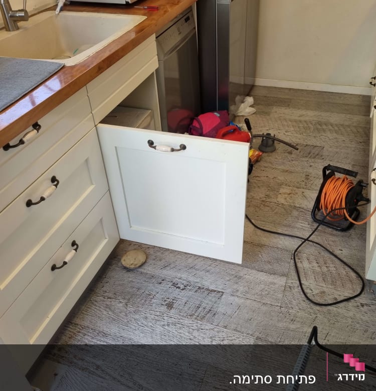 ארון מטבח פתוח עם כבל חשמל וכלי עבודה של אינסטלטור